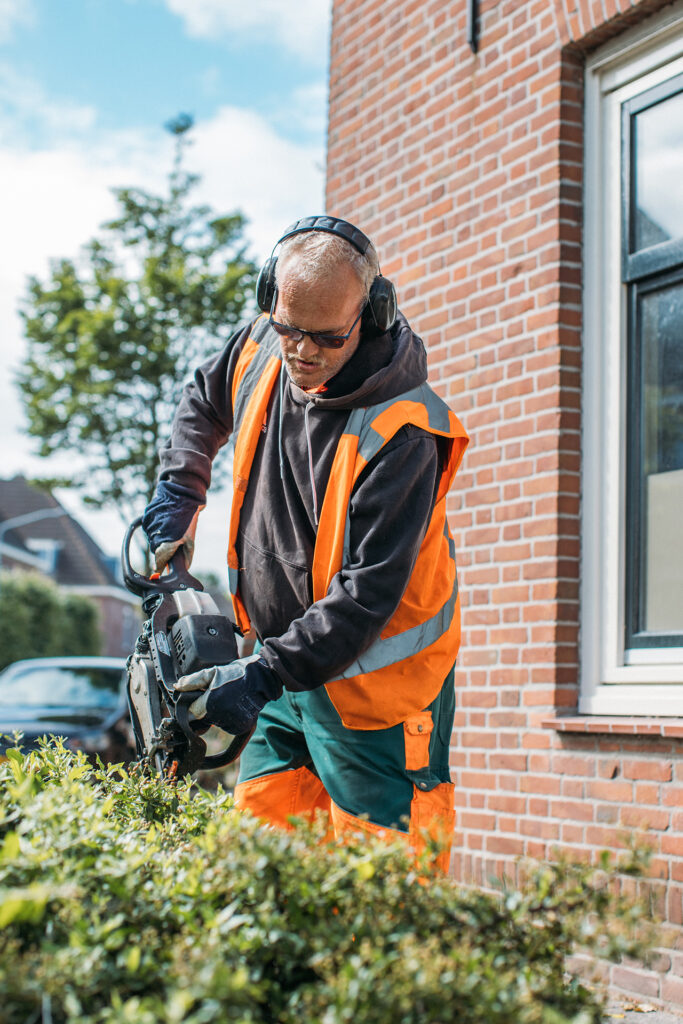 Medewerker van DrechtwerkGroen aan snoeien met heggeschaar